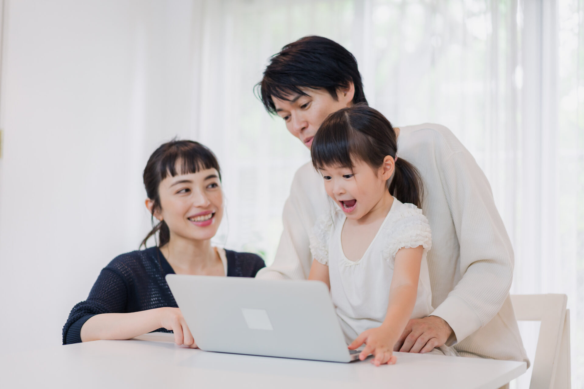 子供と一緒にパソコンで遊ぶ家族